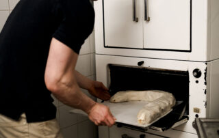 Konditor schiebt hausgemachten Apfelstrudel in den Ofen, eine fotografische Begleitung von Maria Lea in einer Konditorei